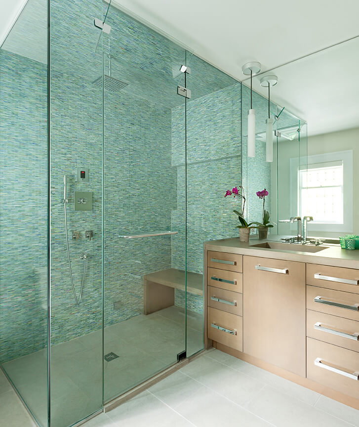 large glass shower with frameless shower door and bench next to sink and miror