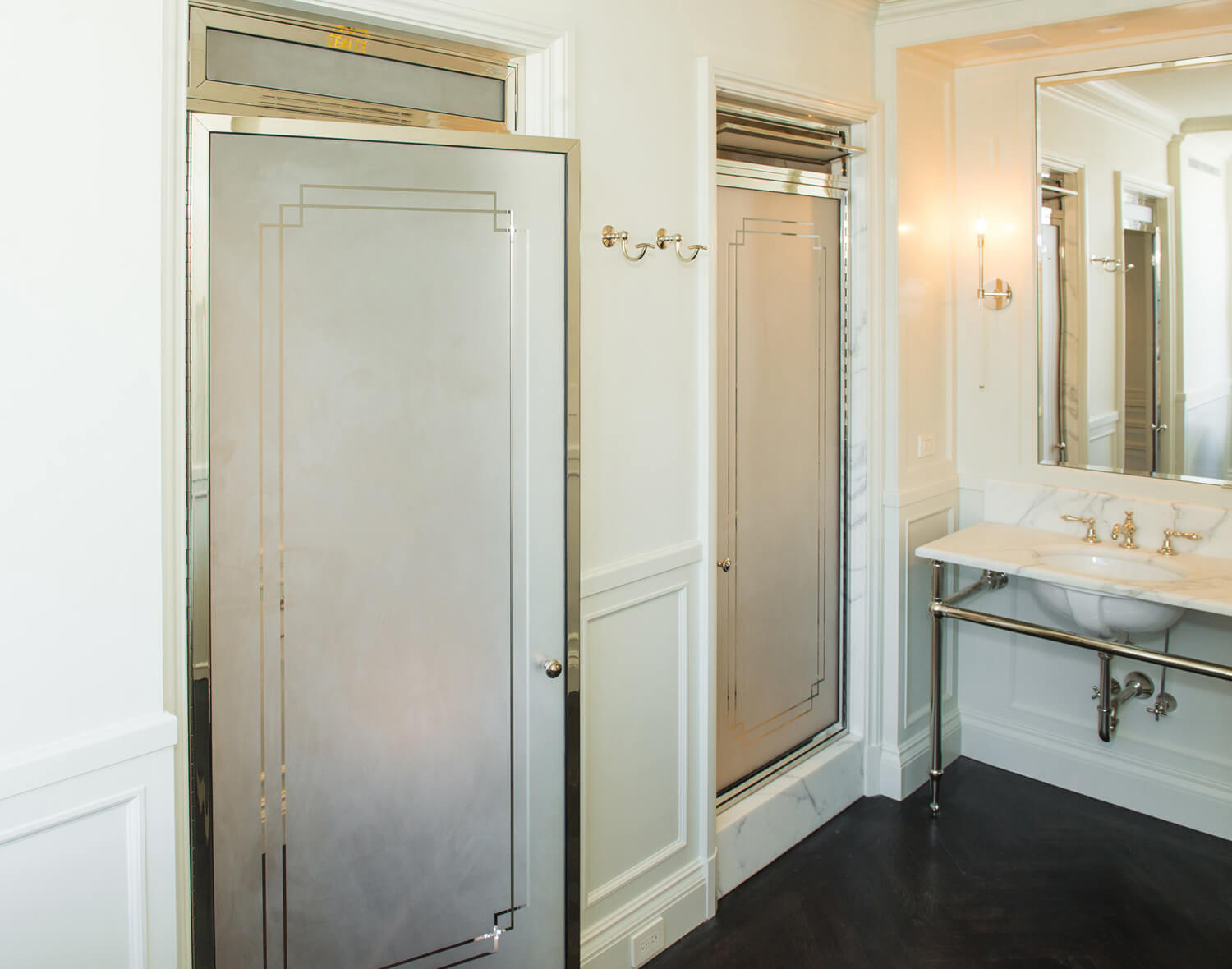 art deco frosted shower and bathroom doors next to a white exposed kitchen sink and mirror