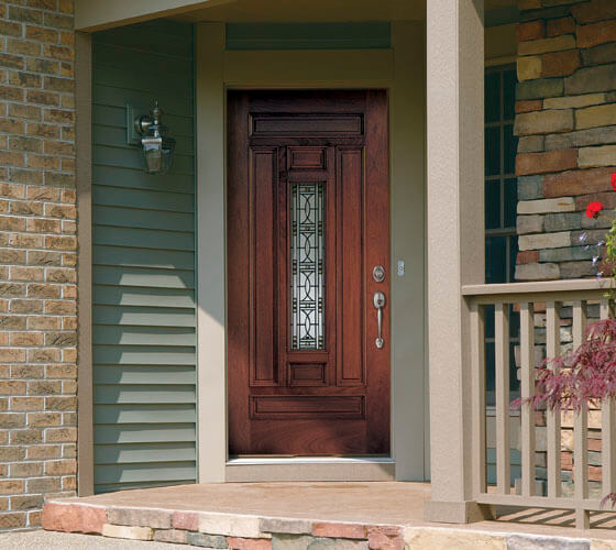 Dark brown door on an olive and brown house with stonework